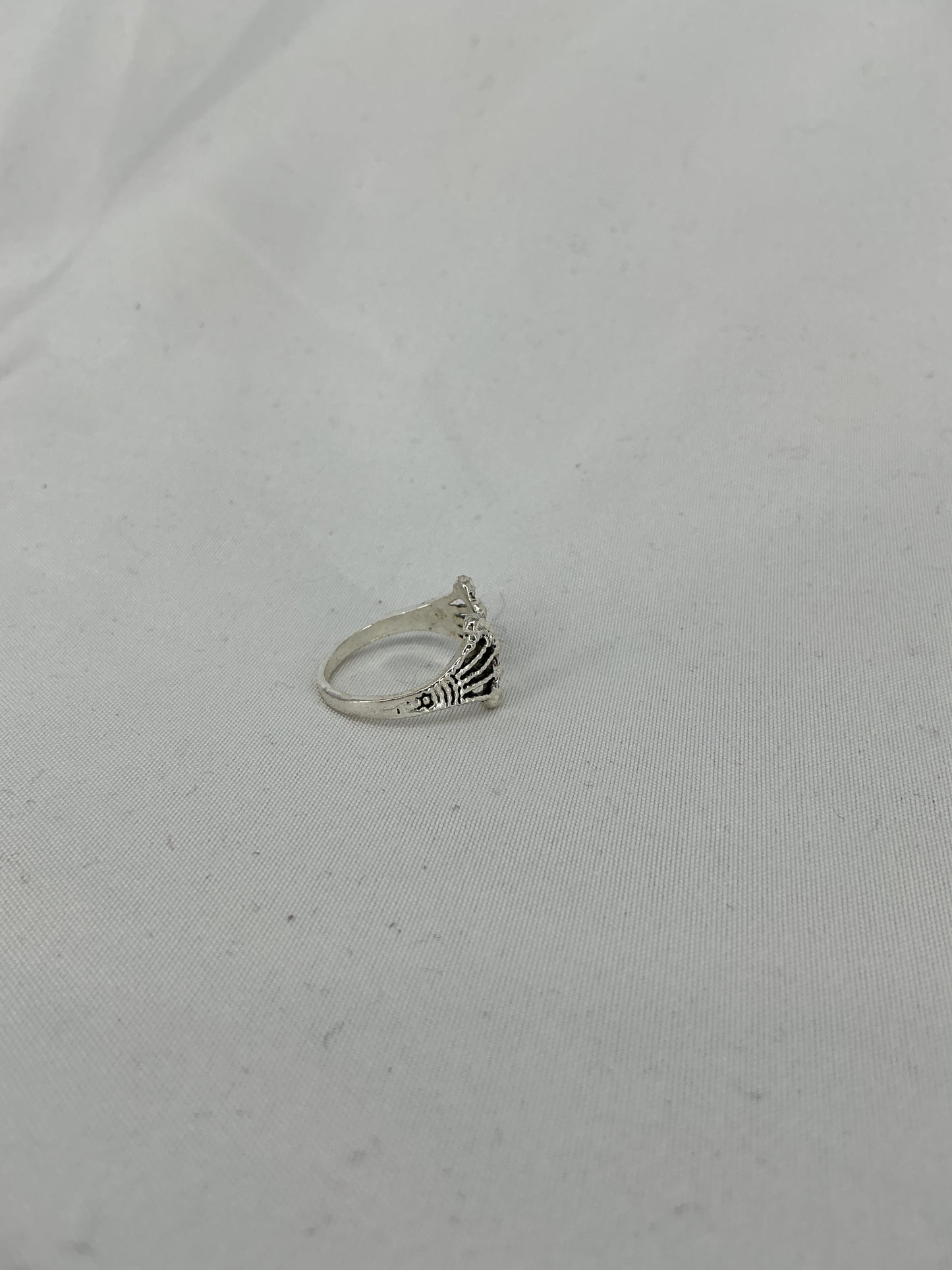 A silver ring, a crown/fan-shaped openwork design with inlaid stones.